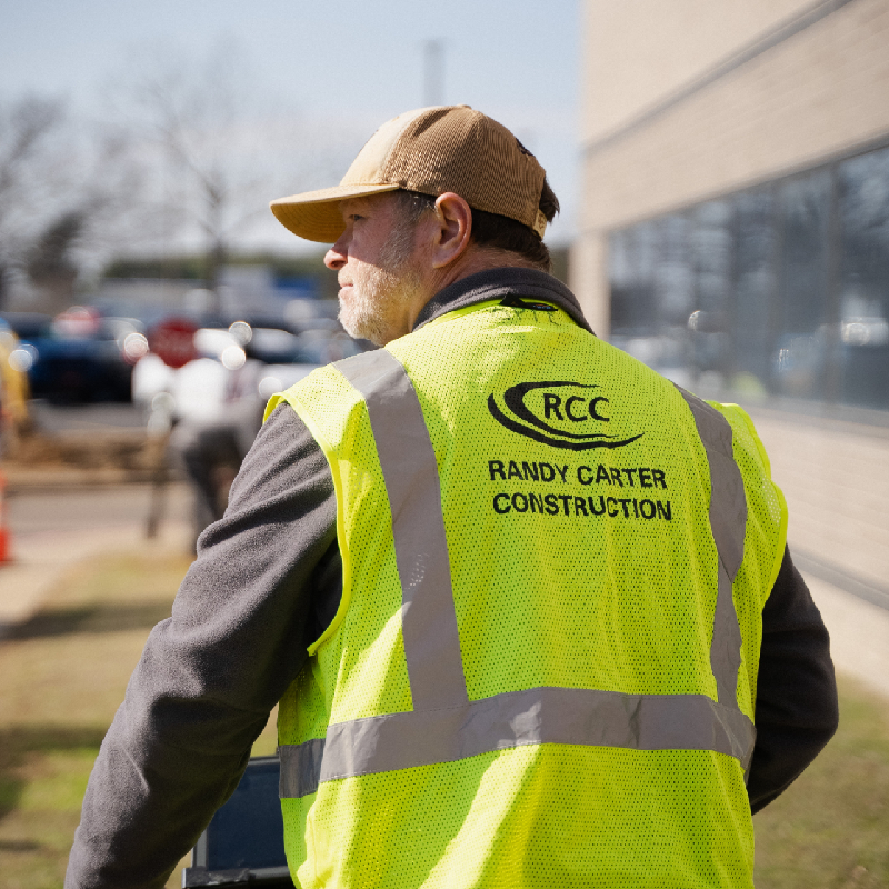 A man wearing a neon green vest with the RCC logo and "Randy Carter Construction" text, along with a hat, representing RCC staff.
